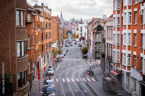 Urban European street with tram tracks, brick buildings and parked cars in Brussels. Perfect for concepts of city life, infrastructure, transportation and travel destinations.