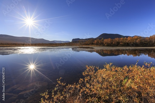 Mountains reflected in lake, autumn colours, sun, sun star, bright, friendly, Nikkaluokta, Laponia, Lapland, Sweden