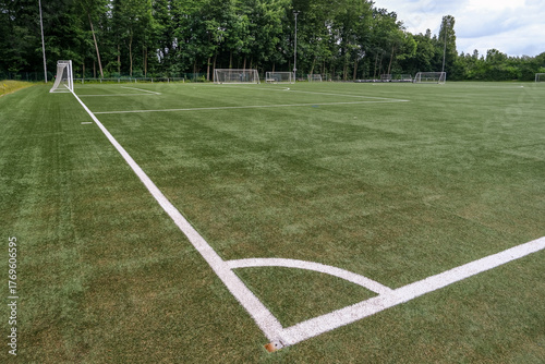 Weiter Blick seitlich von oben auf einen leeren Fußballplatz mit Kunstrasen, weißen Markierungen, Toren und Ausrüstung von Freistoßecke aus, viel Copy Space