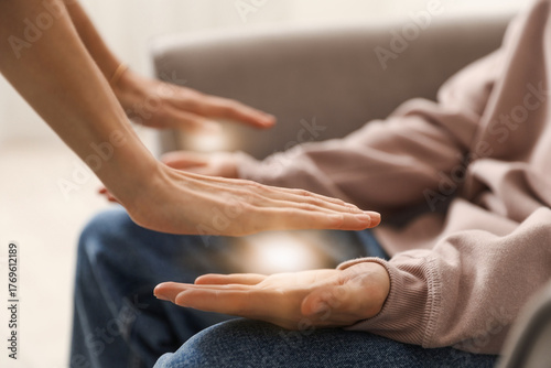Reiki master healing patient's aura during therapy indoors, closeup