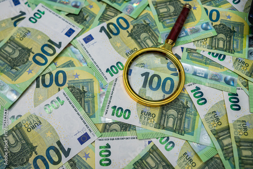 Euro banknotes with magnifier, money inspection, audit, fraud detection and financial control concept