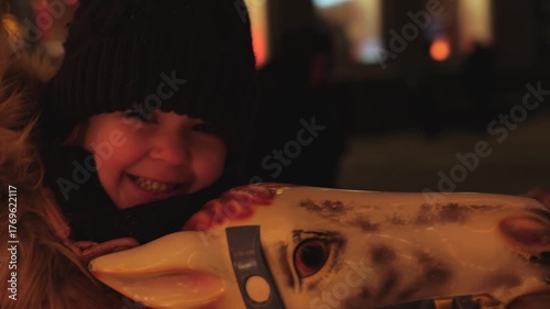 Young child enjoying a snowy carnival ride at night in a festive winter wonderland