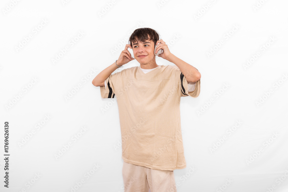 Fototapeta premium young casual dressed Generation Z influencer white male host model teenage boy with wireless headphones for listening to device. plain background studio setting