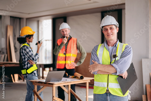Three construction workers are posing for a photo in front of a desk
