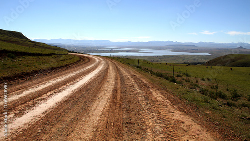 Dirt roads in the QwaQwa villages, located in the mountainous region of the Free State province in South Africa. Trees and plants like Wild Dagga in the foreground. Mountains in the background. 