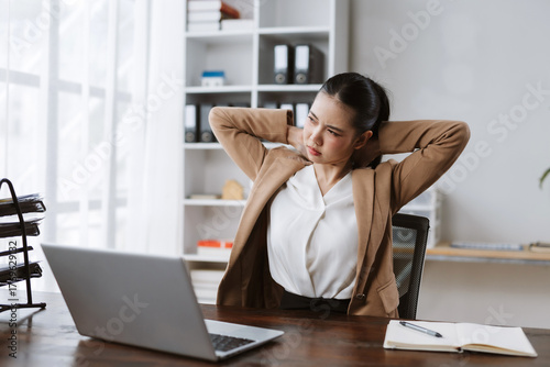 Foto Businesswoman feeling discomfort and pain in her neck and shoulders while workin