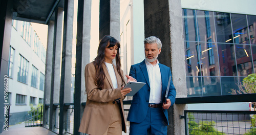 Photos Confident business professionals in formal suits walking and talking outside a m