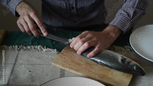 A man cleans fish from scales with a knife