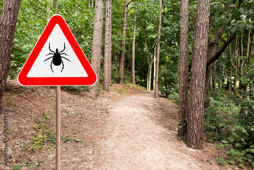 Warning sign marking habitat of ticks in forest