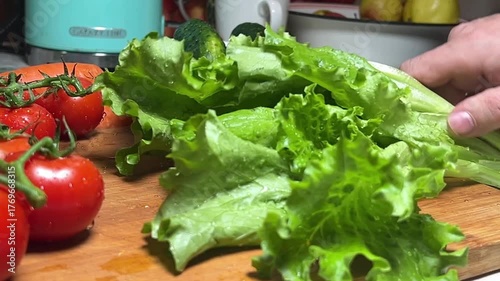 A bunch of fresh lettuce is chopped coarsely on a wooden board. Close-up.