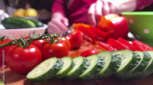 A woman puts sliced tomato slices in a salad bowl.