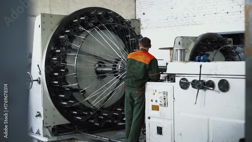 Large circular braiding machine operated by technician amid factory