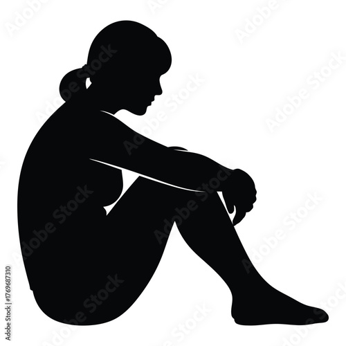 Silhouette of a young woman sitting with head down in a contemplative pose silhouette