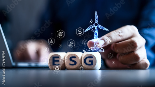 Business executive holding a digital wind turbine above ESG blocks. Illustrating the integration of Environmental, Social, and Governance into corporate strategy and sustainable finance.