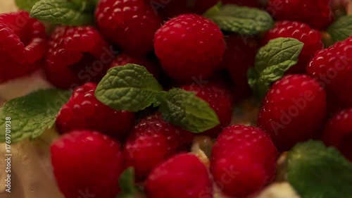 Macro shot of sweet meringue dessert topped with ripe raspberries and mint leaves. Fresh and delicious pavlova-style cake. Concept of homemade dessert, gourmet food, and elegant pastry presentation.