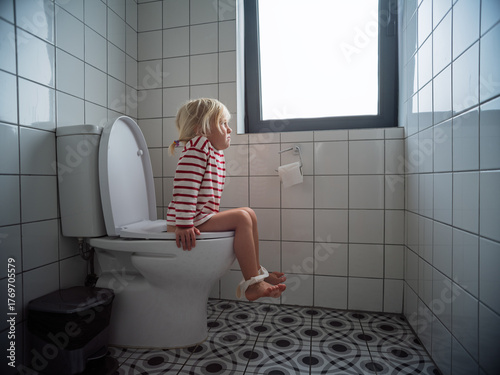 Foto Little 4 year old girl sitting on the toilet during potty training at home