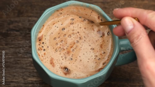 Female hand stir coffee with thick foam