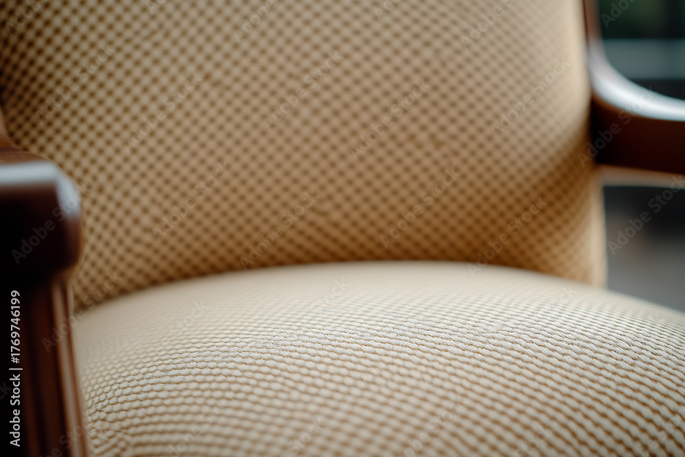 Obraz premium A close-up of a vintage armchair with a cushioned seat and back. The chair features a dark wooden armrest, adding a touch of elegance to its classic design. #vintage #armchair