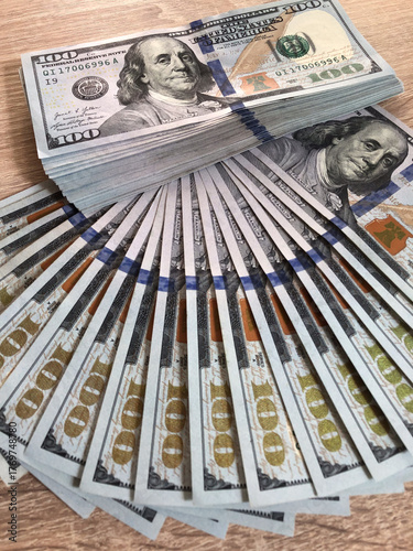 A close-up stack of United States $100 bills neatly arranged and fanned out in an arc, concepts of wealth, savings, financial gain, investment, and abundance.