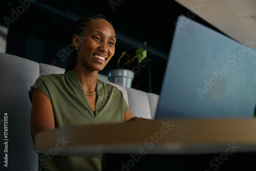 Smiling young black businesswoman using laptop at desk in office