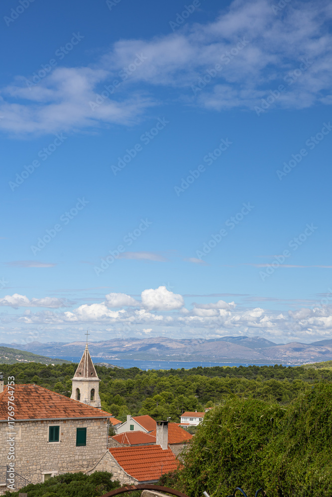 Fototapeta premium Scenic Coastal Village With Stone Houses, Red Roofs and Church Steeple Overlooking the Sea