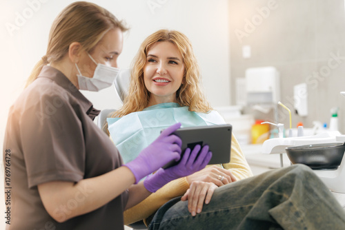 Photos Female caucasian adult at dental appointment with hygienist reviewing treatment