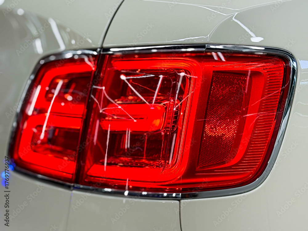 Naklejka premium Red LED turn signal in the rear brake light of the car. Modern car lantern, close-up. Detail on the rear light of a white car. Close-up of a modern green SUV automobile with LED red taillights.