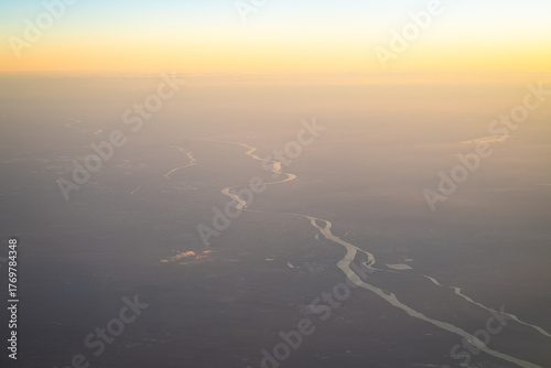 Aerial view of the Danube river gently curving through Budapest, Hungary, bathed in early morning light and calm mist.