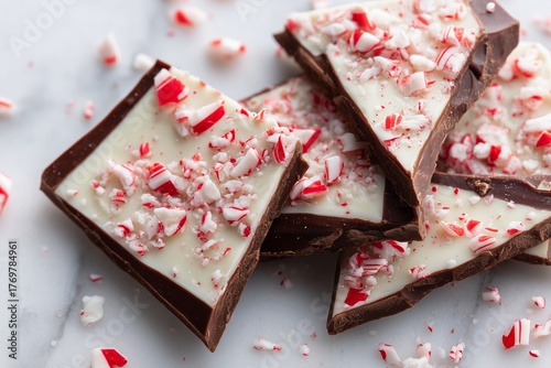 Overhead shot of broken shards of peppermint bark with crushed candy canes on a marble surface, showcasing festive holiday treats and sweet indulgence
