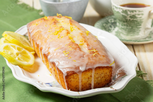 Aromatic lemon cake, covered with sugar icing and sprinkled with zest, served with tea.