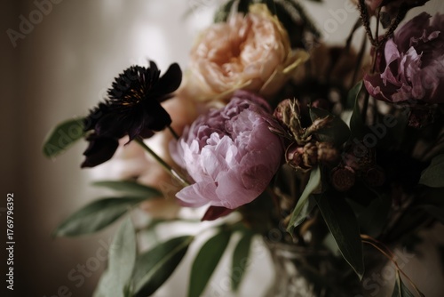 Moody bouquet featuring dried roses and black calla lilies, arranged beautifully in a glass vase, creating an elegant and atmospheric floral display with rich textures
