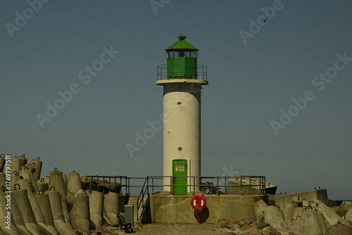 Green lighthouse on pier against clear blue sky