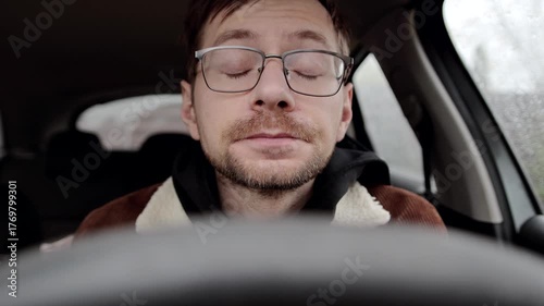 Young sick guy or allergic man sneezing inside a car.