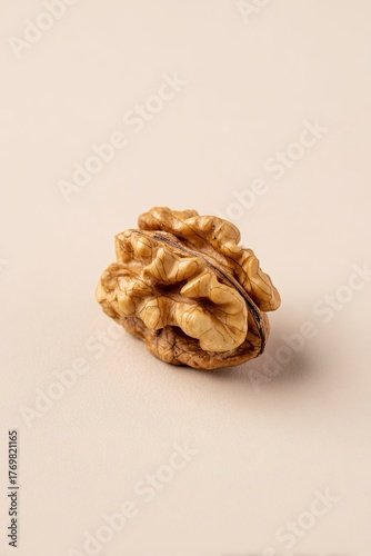 Noce intera, sgusciata su sfondo beige, ripresa in primo piano minimalista.