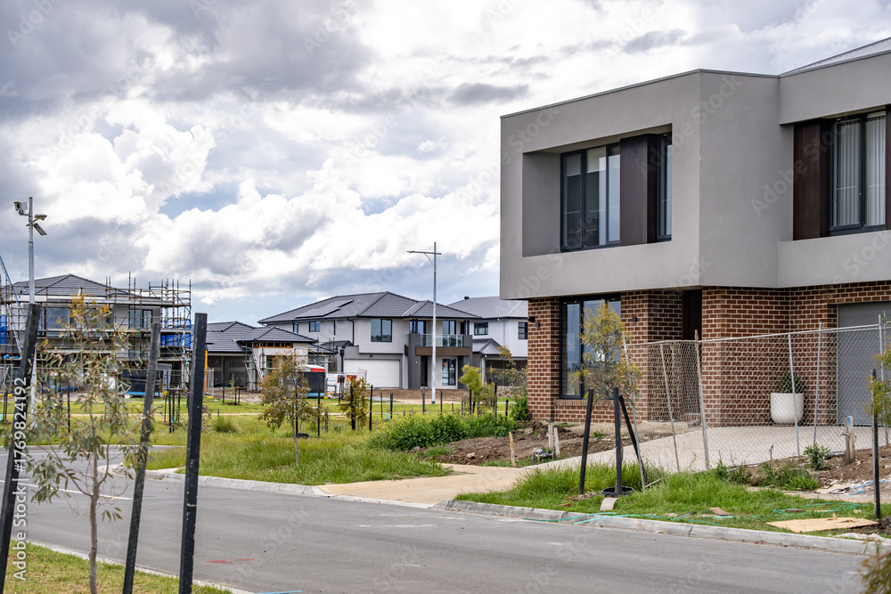 Naklejka premium Newly built modern houses and Contemporary double-storey homes in a developing outer suburb of Melbourne, Australia. Concept of real estate growth, urban expansion, and residential housing.