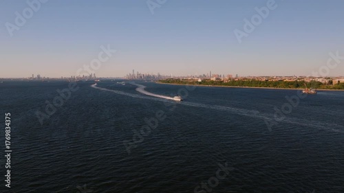 Aerial drone view of a passenger ferry speeding across the Upper New York Bay near Staten Island with city skyline in the distance. ProRes HQ422.