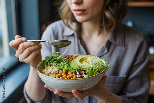 Woman holding healthy buddha bowl with avocado greens and quinoa closeup