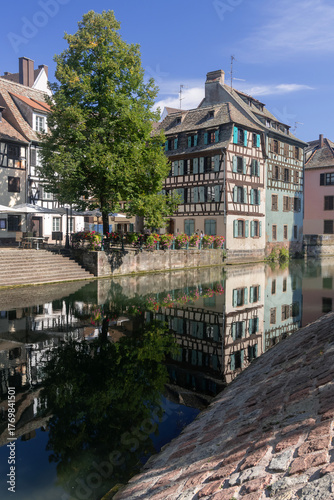 Strasbourg, France - August 26th 2025 : View of the Tanner's Quarter with half-timbered buildings and the Ill river and reflections on the water.