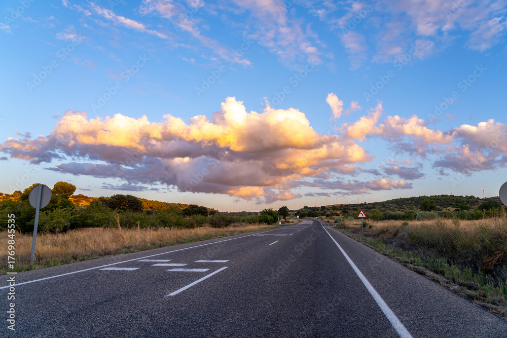 Naklejka premium Empty road under a dramatic sunset sky with clouds.