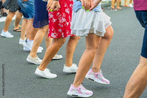 People dancing traditional Bulgarian horo on street, moving rhythmically in line with lively steps, bright summer clothes. Concept of horo dance, tradition, culture, community celebration, folk dance