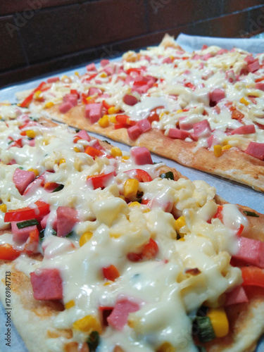 cooking delicious pizza with sausage, tomatoes and cheese at home close-up. ingredients for baking cheese, sausage, tomato sauce and tomatoes, corn, olives. delicious snack for children and adults