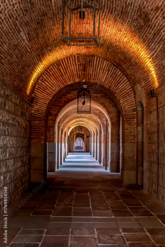 Fototapeta premium Historic brick archway corridor with warm lighting and perspective view