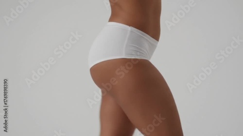 A young woman and fashion model in a white underwear posing and walking with style and elegance in the studio