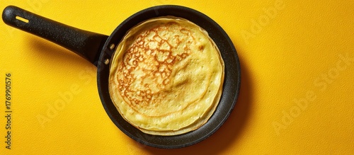 Stack of crepes in a black skillet, laying against a bright yellow background