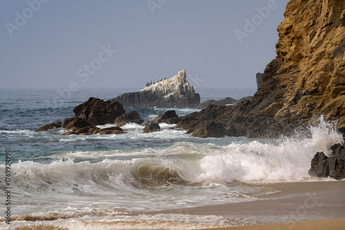 Waves break on the sandy beach of Crescent Bay as waves crash against the rocks in Southern California.