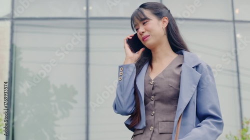 Young happy business businesswoman outdoor walk near modern office for travel, talking on phone, portraying professional communication for urban success on city street.