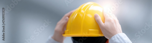 Worker hands adjusting yellow safety helmet strap with bright industrial background for protection