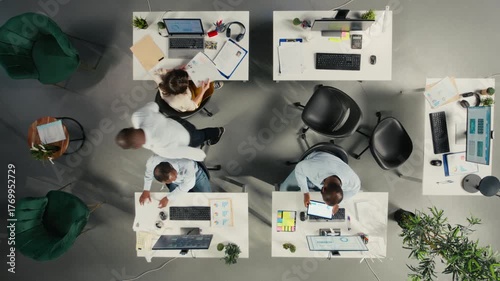 Time lapse top down view of diverse colleagues working in office, focusing on project planning, performance metrics and report sharing. Business people review data for forecasting. Camera A.