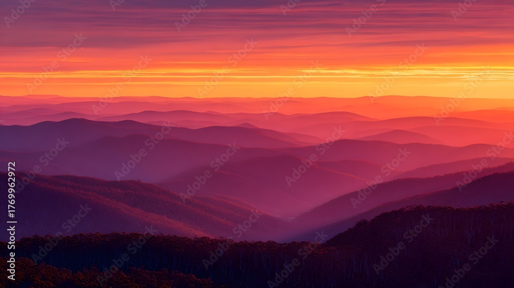Fototapeta premium Layered mountain ranges fade into the distance beneath a dramatically colored twilight sky