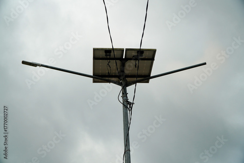 Solar powered street light with two panels against a cloudy sky.